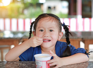 Little asian girl eating ice-cream in cup.