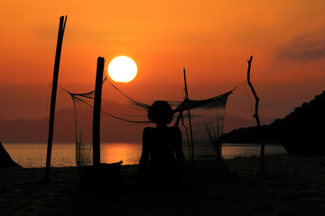 Silhouette of a woman camping alone on the beach with mosquito net