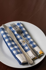 Silverware on the dishcloth, metal fork and knife on the white plate with dishtowel