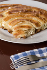 Cheese burek pie on the plate with blurred fork and knife
