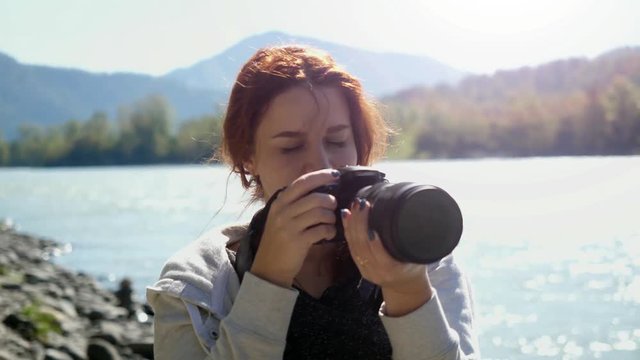 Beautiful woman with red hair photographer taking photo using professional camera outdoors on hike. Female hiker taking pictures outside living outdoor lifestyle in nature landscape. 3840x2160