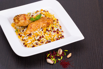 Rice Pilafs Known As Zereshk Polo a Persian Iranian Dish Topped With Saffron Rice Barberries And Pistachio Served With Flavoring Chicken Meat In Tomato Sauce On Wooden Table