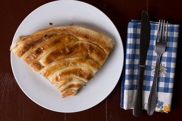 Flat lay above balkan burek cheese pie with silverware on the pl