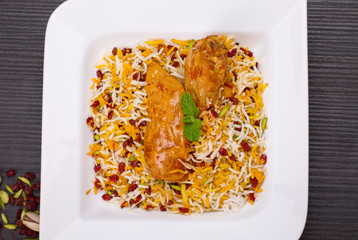 Rice Pilafs Known As Zereshk Polo a Persian Iranian Dish Topped With Saffron Rice Barberries And Pistachio Served With Flavoring Chicken Meat In Tomato Sauce On Wooden Table