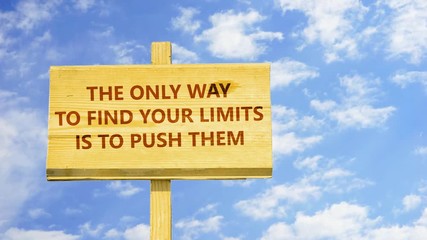 The only way to find your limits is to push them. Words on a wooden sign against time lapse clouds in the blue sky.