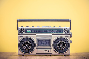 Retro outdated portable stereo boombox radio cassette recorder from 80s front yellow background. Vintage instagram old style filtered photo