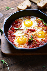 Shakshuka, Fried Eggs with Tomato Sauce in a Pan, Rustic Style and Wooden Background