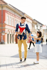 Young father walking with cute daughters on the street