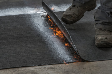 Professional installation of the waterproofing on the concrete foundation. Installation with rolls of bituminous sealing membrane by heating and melting of bitumen rolls by torch to flame while sealin