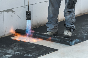 Professional installation of the waterproofing on the concrete foundation. Installation with rolls...