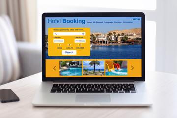 laptop with hotel booking screen on table in room