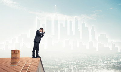 Businessman standing on roof and looking in binoculars. Mixed me