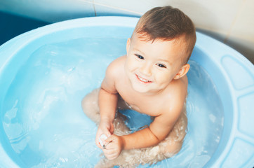 Happy child boy swims in the bathtub