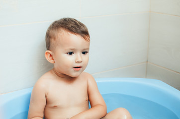 Happy child boy swims in the bathtub