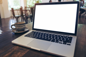Mockup image of laptop with blank white screen on wooden table in vintage cafe