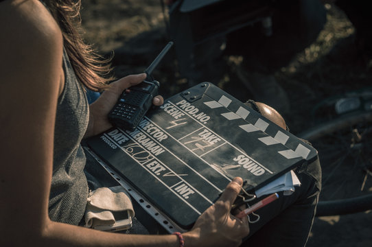 Woman holding clapperboard against her face