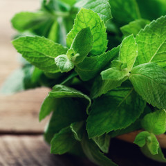Fresh mint leaves on wooden background with copyspace and sunlights