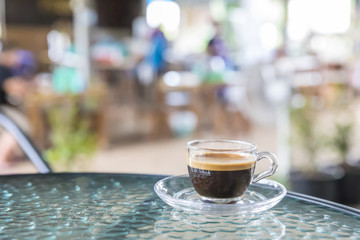 A cup of hot coffee on the glass table for relax.