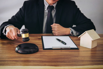 Male lawyer or judge hand's striking the gavel on sounding block, working at courtroom for decide home insurance, Law and justice concept, Settle a house dealing lawsuit