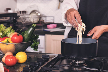 female housewife making homemade pasta with flour and eggs over table in kitchen