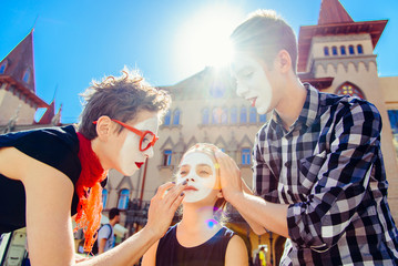 a family of mimes is preparing for a show on the street