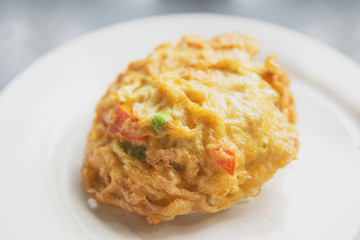 Omelette with peas and tomato wrapped rice on white plate
