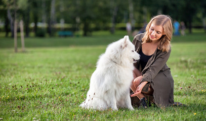 Pretty young girl with her samoyed dog at the park
