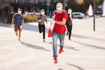 a group of mimes runs after a thief who stole a bag