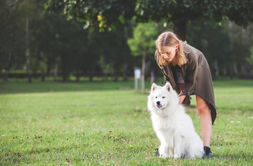 Pretty young girl with her samoyed dog at the park