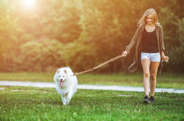 Girl walking dog at the park, samoyed