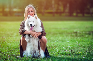 Obraz na płótnie Canvas Pretty girl playing with her dog in the park, samoyed