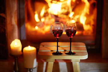 Two glasses of red wine near fireplace
