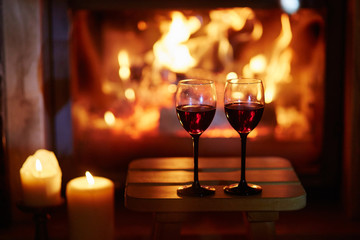 Two glasses of red wine near fireplace