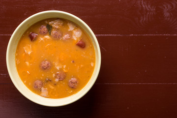 Flat lay above cooked beans with sausages on the wooden table with copy space