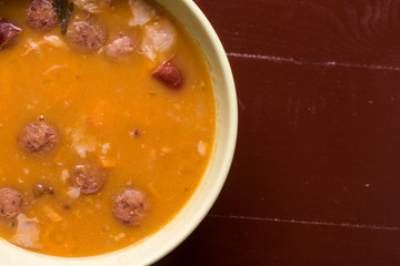 Flat lay above cooked beans with sausages on the wooden table with copy space