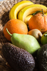 A fruit platter with bananas, oranges, kiwis, pears and avocado
