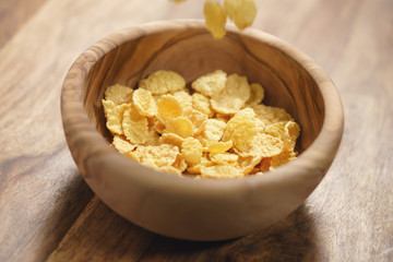 corn flakes falling into wood bowl closeup