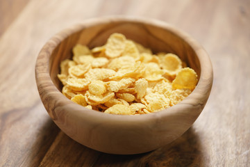 corn flakes falling into wood bowl closeup