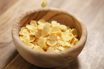 corn flakes falling into wood bowl closeup