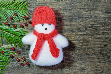 Christmas and new year composition, background. Snowman in red cap and scarf, branch of winter spruce on a wooden table vintage. Flat lay, top view 