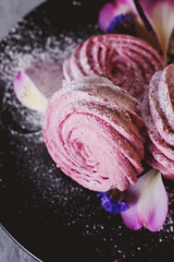 sweets and desserts, soft, airy and sweet pink currant or berry marshmallows with powdered sugar on a gray background