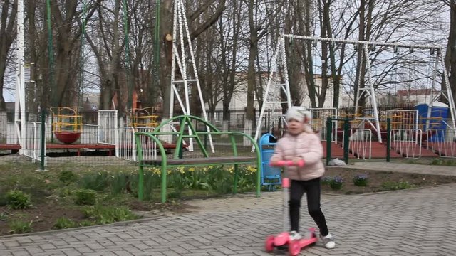 Children run and ride a scooter in the Park