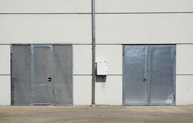 Obraz na płótnie Canvas White Overhead Steel Garage Door On Exterior Of Beige Metal Building With Red Bumper Posts