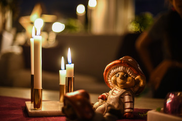 A Christmas figurine on a table with lit candles