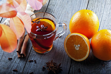 hot tea with spices and orange amid autumn leaves