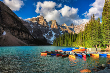 Morning light on colorful canoes along the shore of Moraine Lake, Banff National Park, Alberta,...