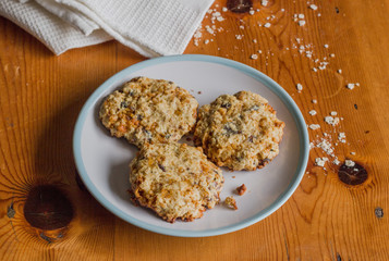 Homemade sweet and crunchy oats cookies on rustic bright wooden kitchen table with oats and white cloth - Food background