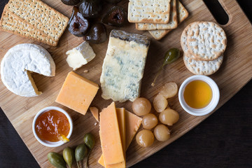 Cheese board serving with figs, caper berries, jam and pickled onions. Top view photograph with copy space