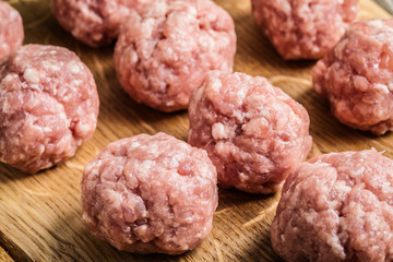 Raw meatballs on the wooden cutting board.