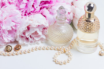 Female lifestyle with fresh pink peony flowers, glamour bottles and jewellery close up